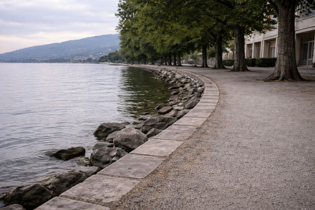 Chemin piéton vide au bord du lac de Neuchâtel, vue à hauteur d’homme, illustrant une vigilance continue sans direction ni apaisement